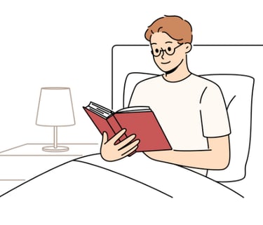 a man reading a book in bed with a lamp on the side