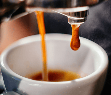 a person is pouring a cup of coffee into a cup