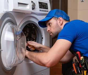 a man in a blue shirt is fixing a washing machine