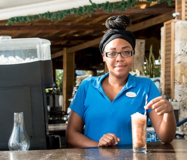 a woman in a blue shirt is holding a drink