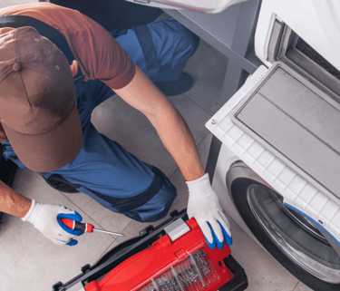 a man in a red shirt is fixing a washing machine