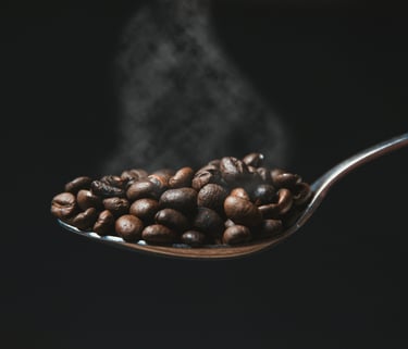 A spoon with freshly roasted coffee beans with fresh smoke visible