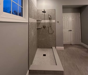 Interior view of glass-enclosed shower with stainless steel fixtures and mosaic tile floor