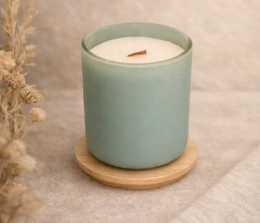 Vela de soja perfumada en un frasco de vidrio verde salvia mate con una mecha de madera sobre un pos