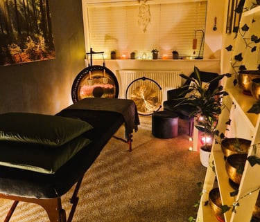 Studio with treatment couch, chair, gongs and shelf with Himalayan singing bowls