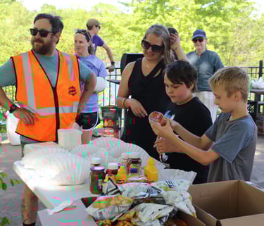 A group at the food table putting condiments on their hot dogs