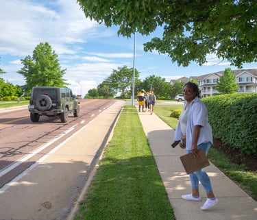 Full-body shot of Sophia Smith walking down a sidewalk with a clipboard in hand
