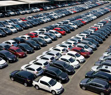 Vista aérea de grande pátio de concessionária com dezenas de carros usados organizados em fileiras