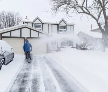 a person using a snow blower to clear snow from the driveway