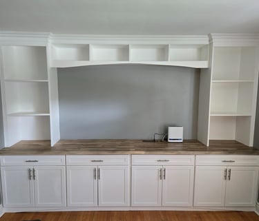 Custom white built-in wall unit with wood countertop, open shelving, and shaker cabinets.