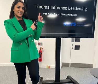 A photo of Anita standing in front of a large screen with a presentation on.