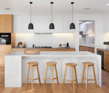 Open-concept kitchen with large island, wooden bar stools, pendant lights, and sleek cabinetry in a modern home