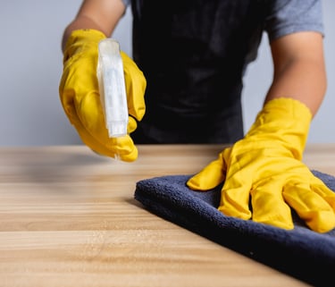 une personne portant des gants jaunes nettoyant une table a l'aide d'un chiffon d' un produit .