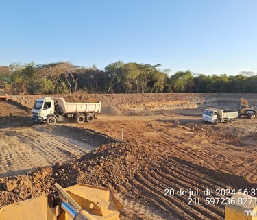 Canteiro de obras com caminhões basculantes e terraplanagem em execução em área aberta no MT