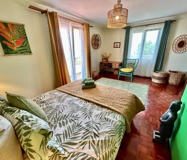 Tropical style bedroom featuring botanical bedding, bamboo decor, and a sunny balcony view.