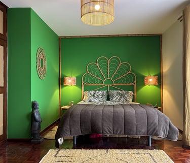 Tropical bedroom interior with green walls, rattan headboard, and warm boho lighting decor.