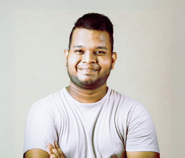 Smiling man with folded arms wearing a light shirt in front of a neutral background
