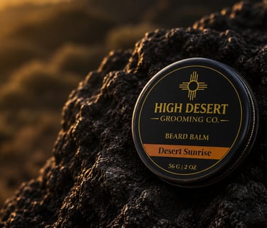 High Desert Grooming Co. Desert Sunrise beard balm tin resting on a rugged desert rock at sunset.