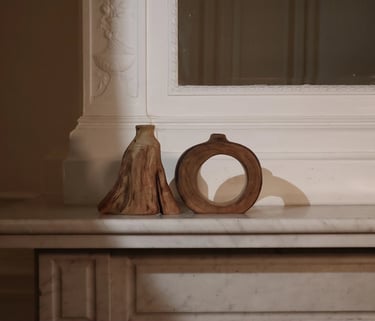 Hand-turned wooden vessels and decorative bud vases displayed on a shelf with moody interior lighting.