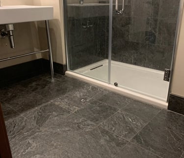 Spotless bathroom featuring a clean glass shower enclosure and scrubbed dark tile floors after a dee