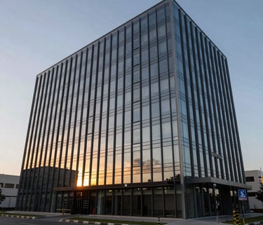 A wide-angle photograph of the Zoevita headquarters, a sleek modern building with large glass windows reflecting a South Asian sunset.