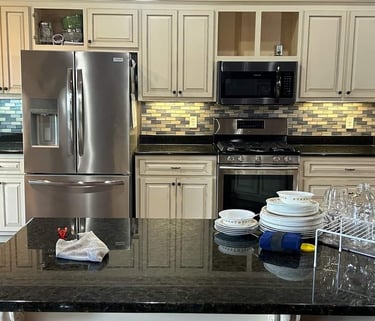 Kitchen remodel with white cabinets, stainless steel appliances, and a dark countertop island.