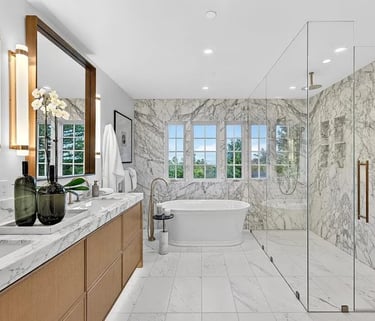 Bathroom remodel with a freestanding bathtub, marble tile, and glass-enclosed shower.