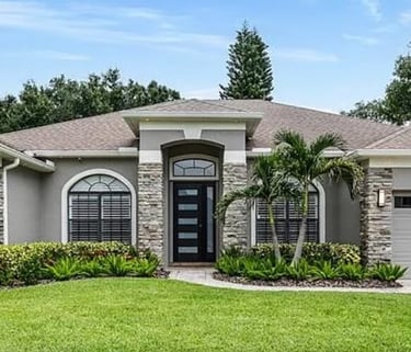 Exterior of a single-story home with a stone-accent facade, front entry door, and attached garage.