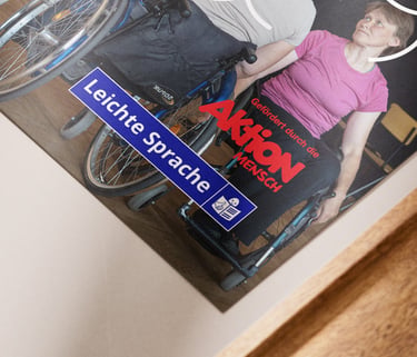 Auf einem Tisch liegt ein Flyer. Das Logo von AktionMensch und Leichte Sprache ist abgebildet.