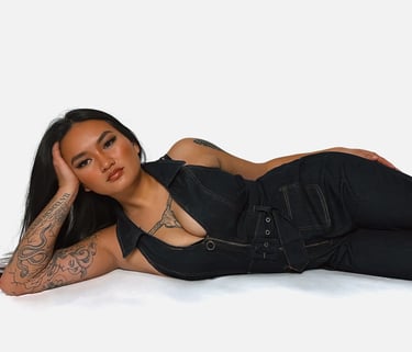 Amelia laying on the ground in a denim jumpsuit with her hand on her head