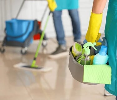 two people standing  one with mop and the other with cleaning supplies
