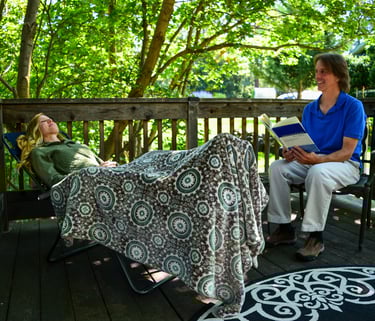 woman in hypnotherapy session with male practitioner on an outside deck