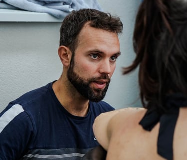 A bearded man looks intently at a woman sitting in an outdoor cold plunge ice bath.
