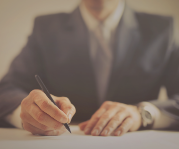 a man in a suit and tie is writing on a piece of paper