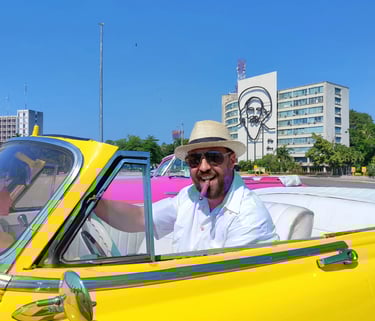 Smiling man with cigar in a classic yellow convertible car at Revolution Square in Havana, Cuba.