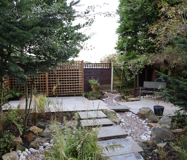 A garden design in Bury, Manchester showing stepping stones leading to a raised patio