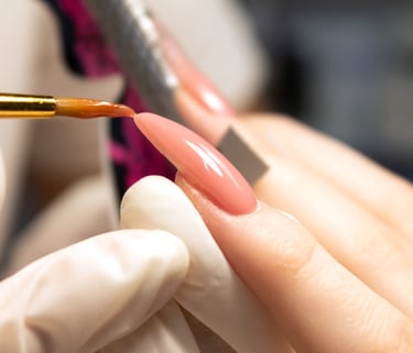 a person is holding a nail brush and is forming acrylic nails