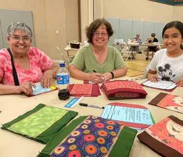 3 women tracing liners for Days for Girls at 3rd Thursday Humanitarian Day