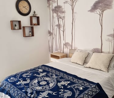 a bed with a blue blanket and a clock on the wall