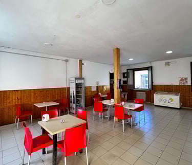 a bar with red chairs and tables and a refrigerator