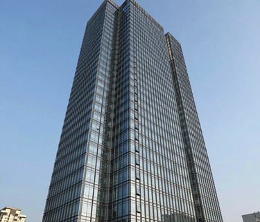 A wide-angle professional photograph of a modern glass skyscraper in a South Asian business district, reflecting a clear blue sky, representing corporate strength and reliability.