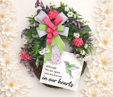 Memorial wreath with hummingbird sign, floral arrangement, and pink ribbon for sympathy decor.