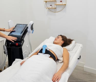 woman sitting on clinic bed with emsculpt machine on stomach