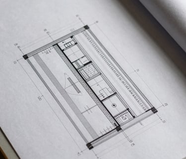 Close overhead shot of architectural drawing sheets on a drafting table, dense dimension annotations and code reference notes visible in sharp focus, task lighting casting clean hard shadows across the paper surface