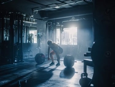 A determined female athlete performing a heavy barbell deadlift in a moody, sunlit gym.