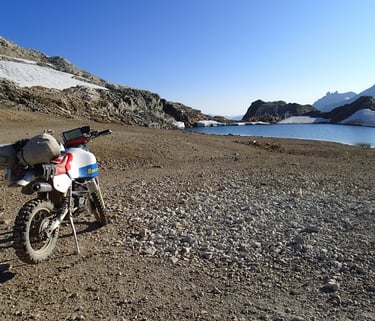 a motorcycle parked on a rocky beach next to a body of water