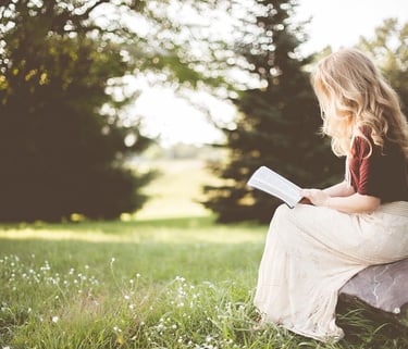 a woman sitting on a rock with a book
