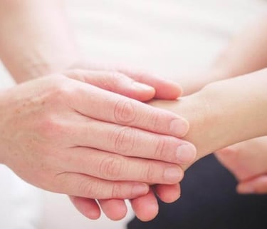 Hands gently holding a wrist in a gesture of care and support.