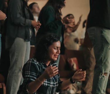 a woman kneeling down and people praying together