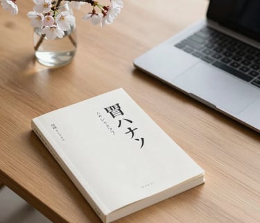 Clean, high-angle photography of a minimalist wooden desk with a Japanese language textbook, a sleek modern laptop, and a delicate branch of cherry blossoms in a glass vase, soft natural morning light.